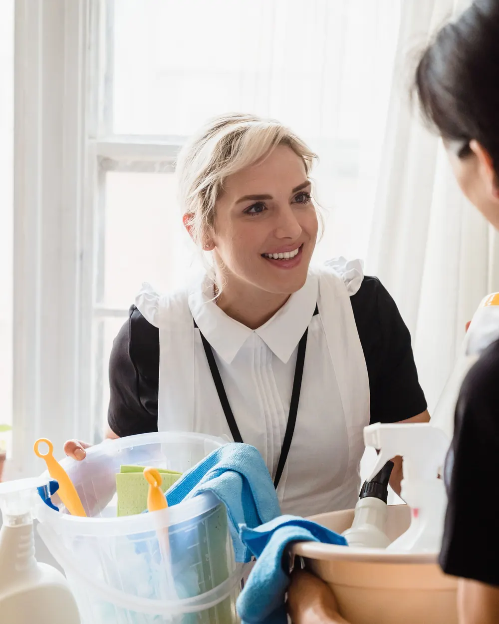 Smiling cleaner arriving with a caddy of supplies for an Airbnb changeover clean