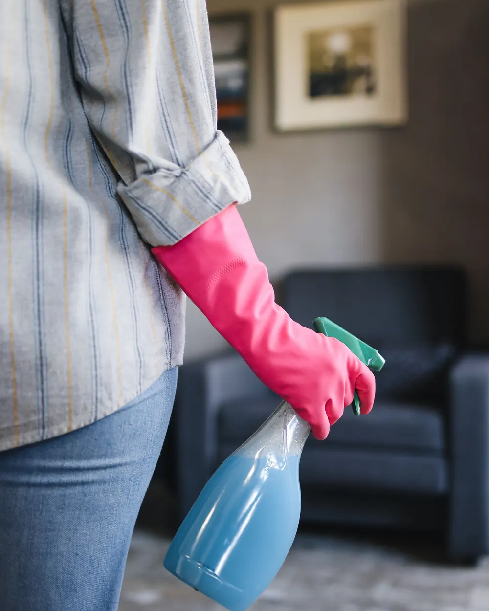 Cleaner with spray bottle cleaning a living room before tenants move out
