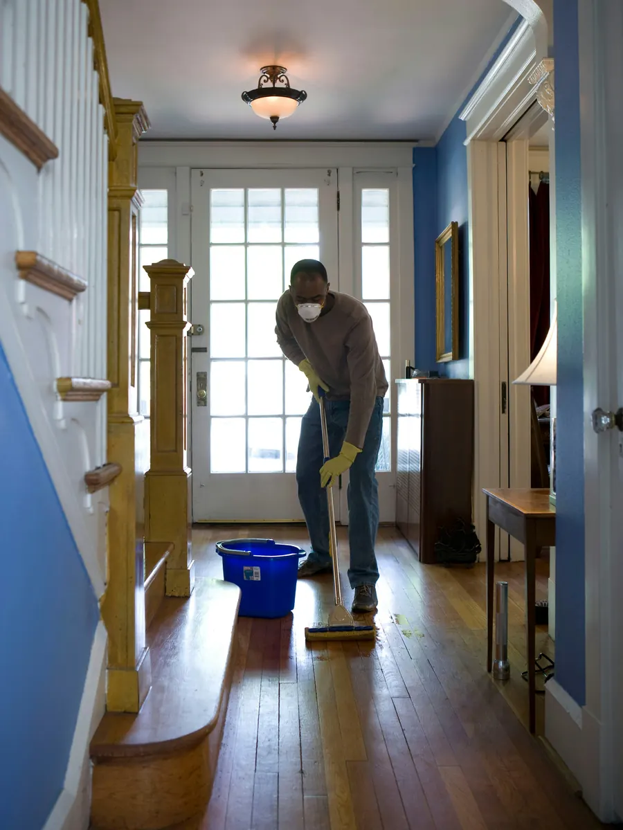 House cleaner mopping a hallway floor during a regular home clean