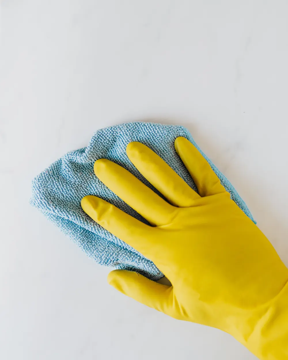 Gloved hand wiping a marble kitchen worktop with a microfibre cloth
